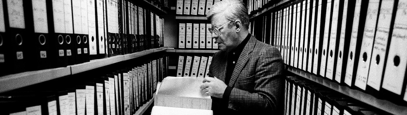 Bild, auf dem der Politiker Helmut Schmidt zwischen Regalen voller Ordner zu sehen ist. Er blättert in einer Akte. Das Bild verlinkt auf die Internetseite des Archivs der Friedrich-Ebert-Stiftung.