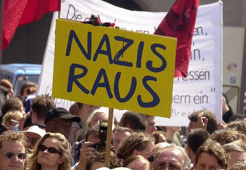 Bild, das Demonstrant_innen zeigt, die Plakate und Transparente hochhalten. Das Plakat in der Mitte hat die Aufschrift: “NAZIS RAUS”. Das Bild verlinkt auf eine Internetseite der FES mit Informationen zum Thema Rechtsextremismus.