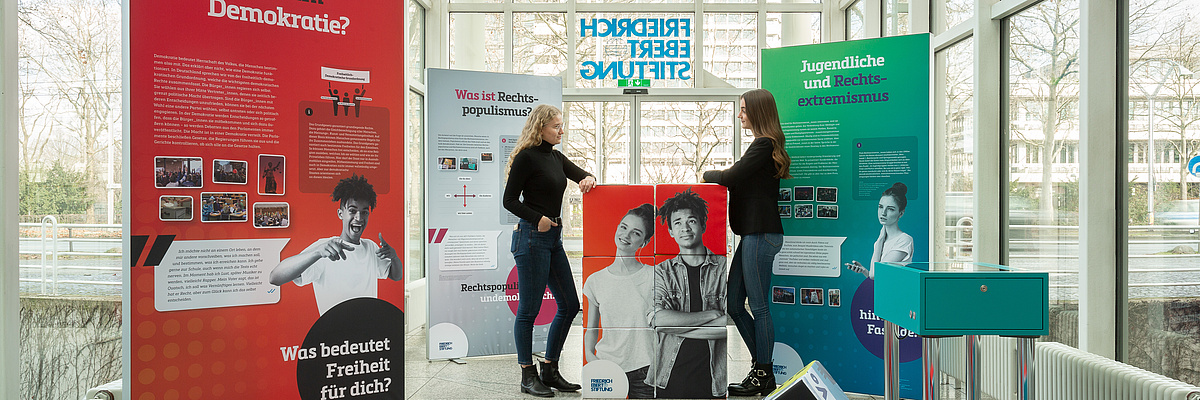 Zwei junge Frauen stehen im Eingang der FES Bonn und schauen sich die Ausstellung an